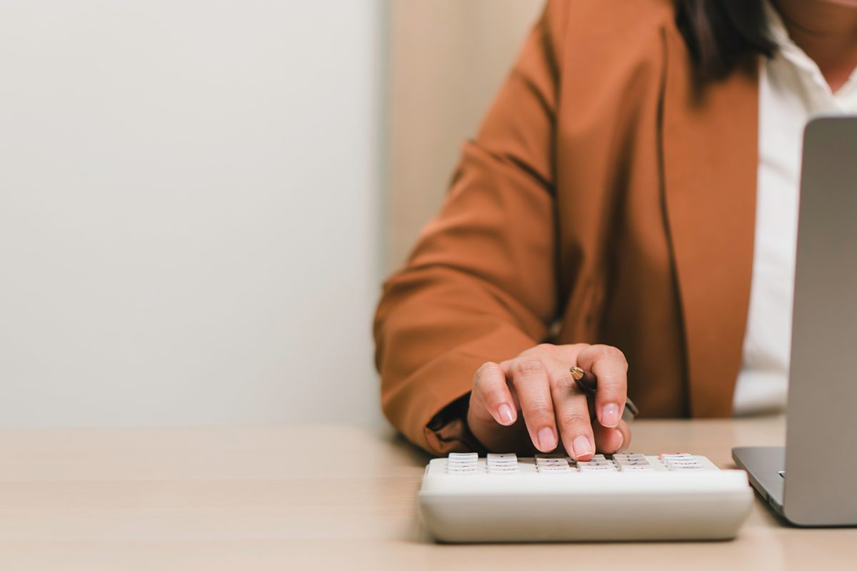 Financial accounting and business budgeting concept. Professional calculating business expenses with calculator and laptop, illustrating finance management, audit, and economic planning.